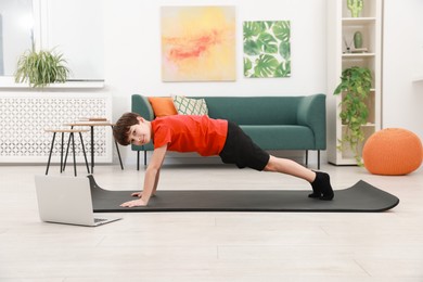 Photo of Boy having training with online coach via laptop at home