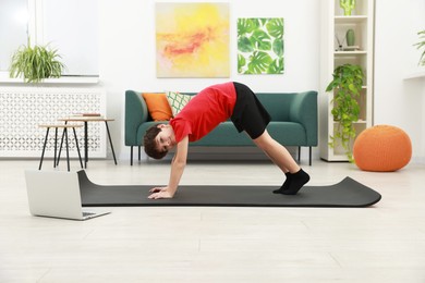 Photo of Boy having training with online coach via laptop at home