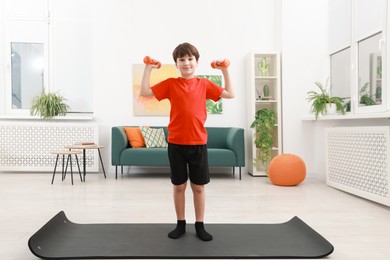 Photo of Boy training with dumbbells at home. Sport activity