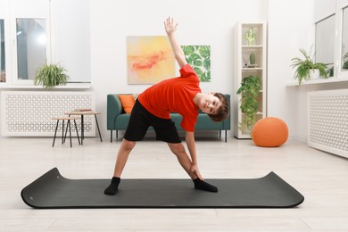 Photo of Boy doing exercise on fitness mat at home. Sport activity