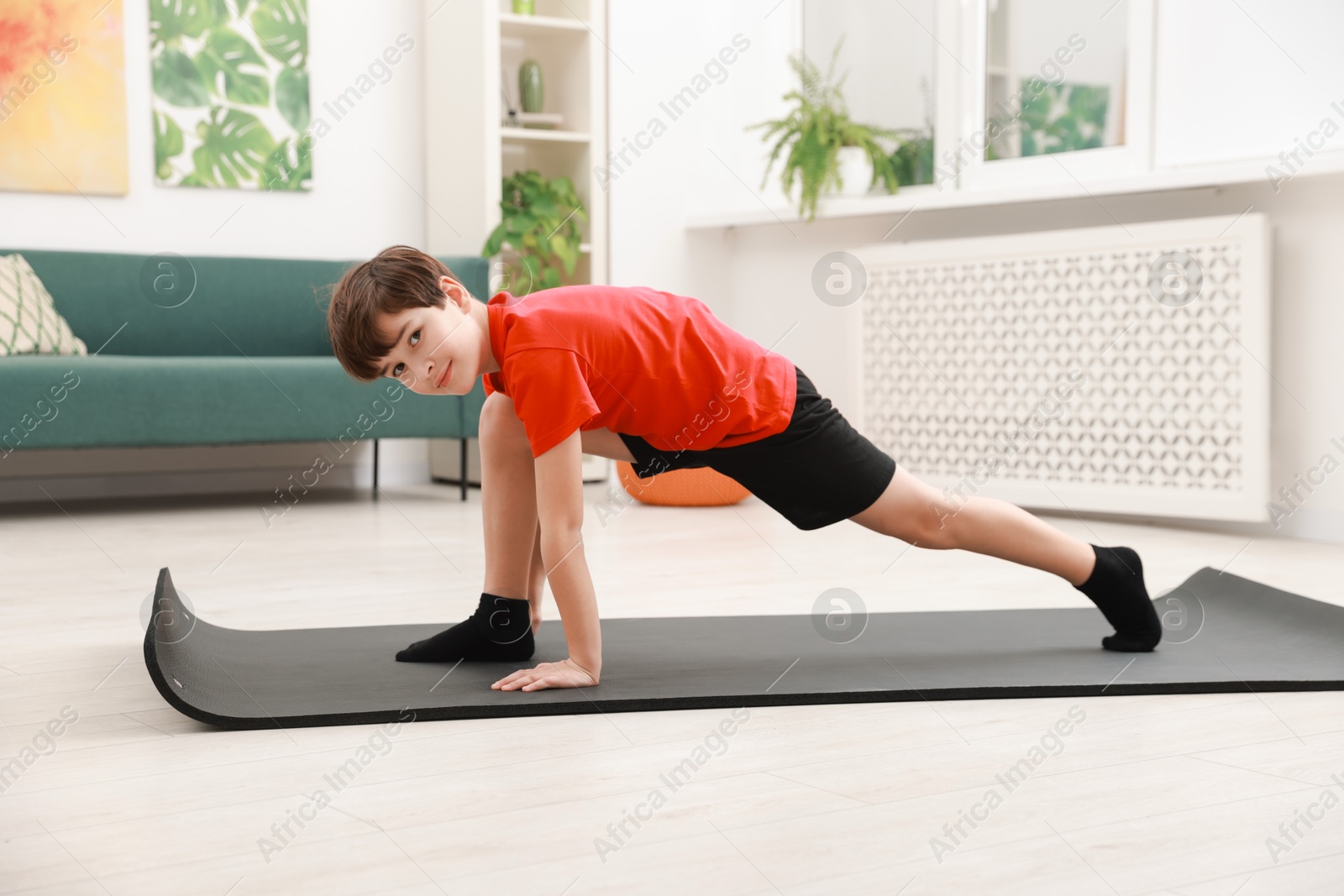 Photo of Boy doing exercise on fitness mat at home. Sport activity