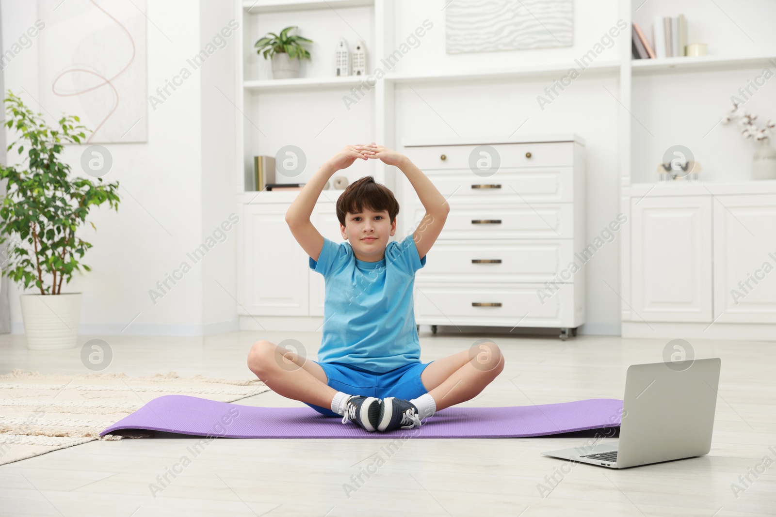 Photo of Boy having training with online coach via laptop at home