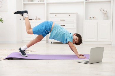 Photo of Boy having training with online coach via laptop at home