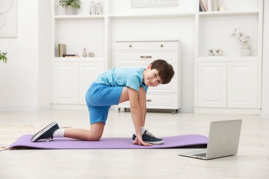 Photo of Boy having training with online coach via laptop at home