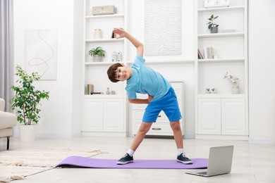 Photo of Boy having training with online coach via laptop at home