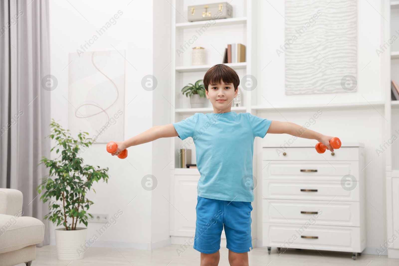 Photo of Boy training with dumbbells at home. Sport activity