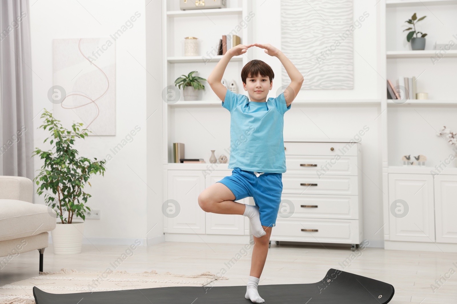 Photo of Boy doing exercise on fitness mat at home. Sport activity