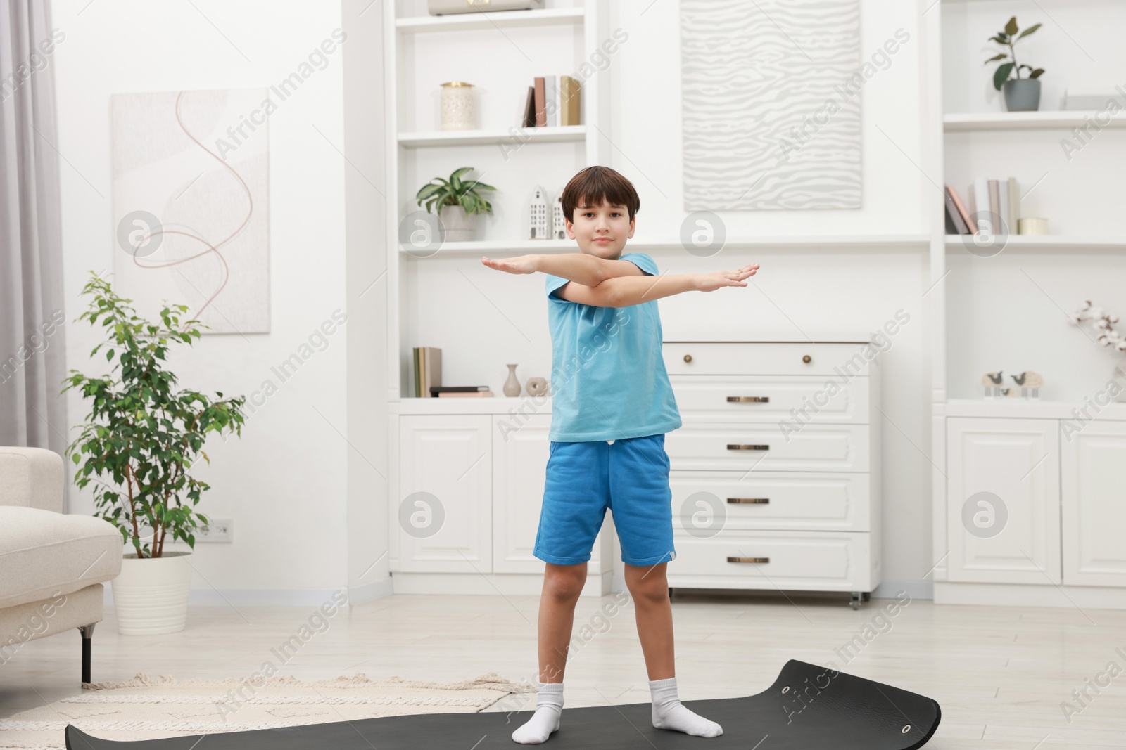 Photo of Boy doing exercise on fitness mat at home. Sport activity