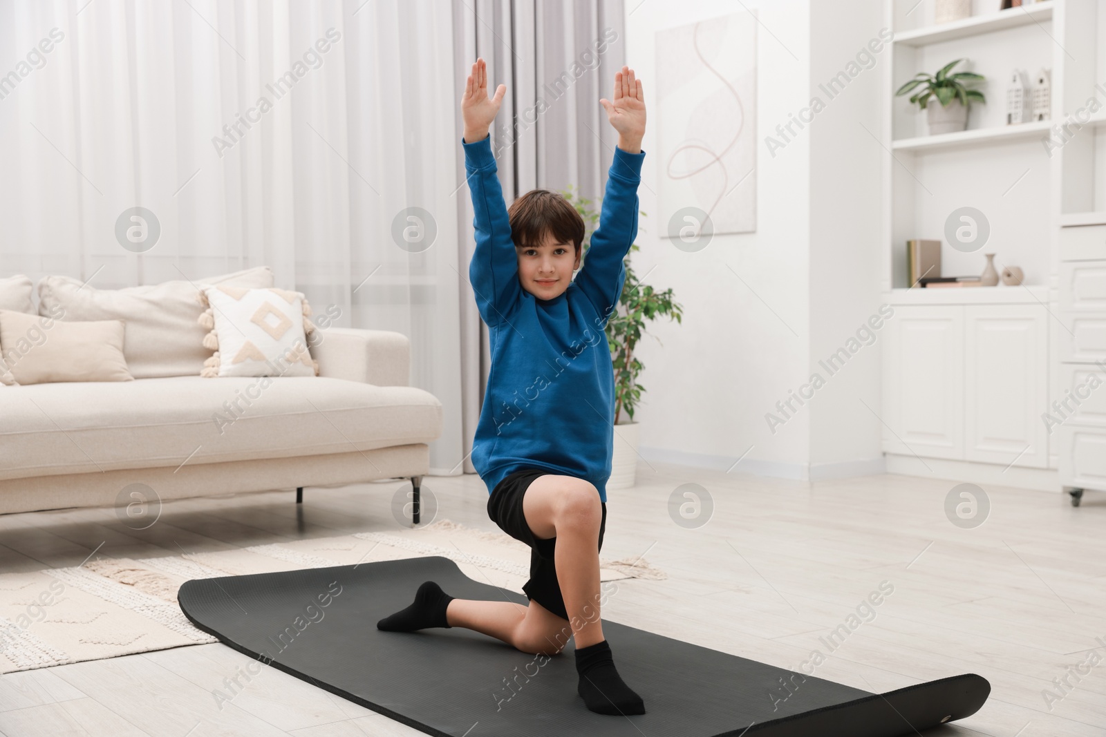 Photo of Boy doing exercise on fitness mat at home. Sport activity