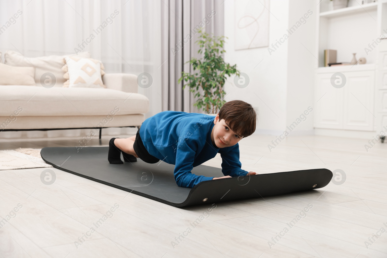 Photo of Boy doing exercise on fitness mat at home. Sport activity