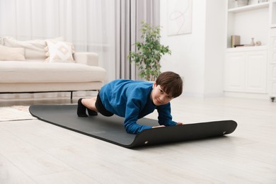 Photo of Boy doing exercise on fitness mat at home. Sport activity