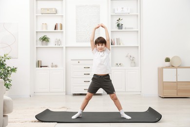 Photo of Boy doing exercise on fitness mat at home. Sport activity