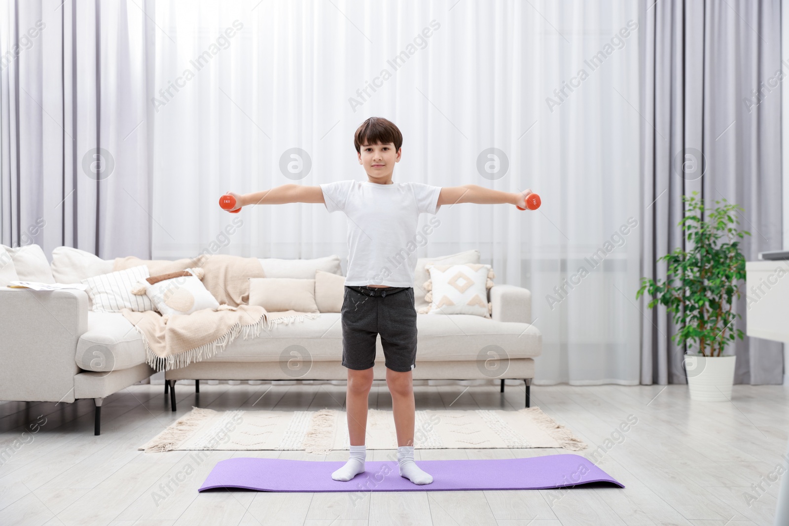 Photo of Boy training with dumbbells at home. Sport activity