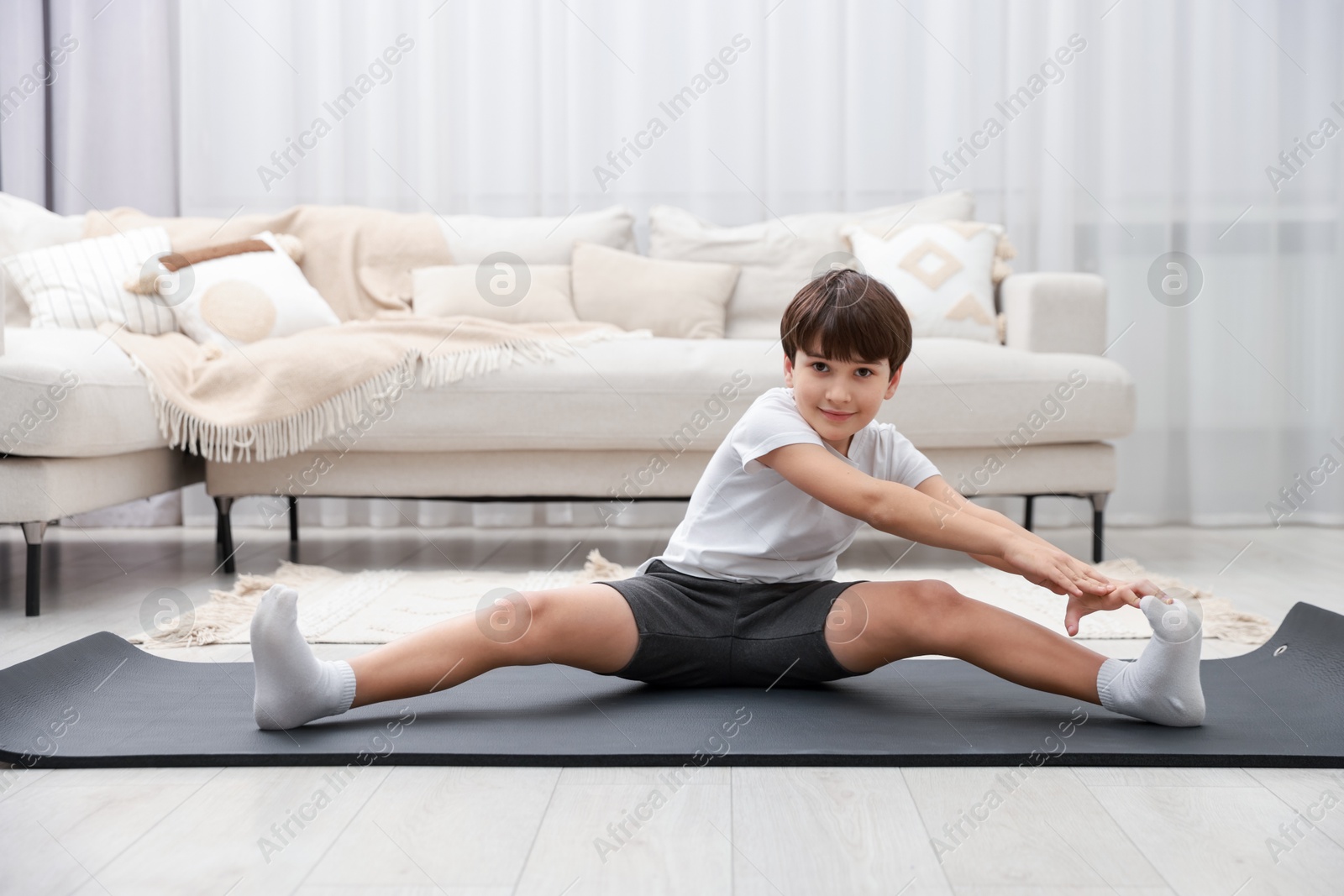 Photo of Boy doing exercise on fitness mat at home. Sport activity