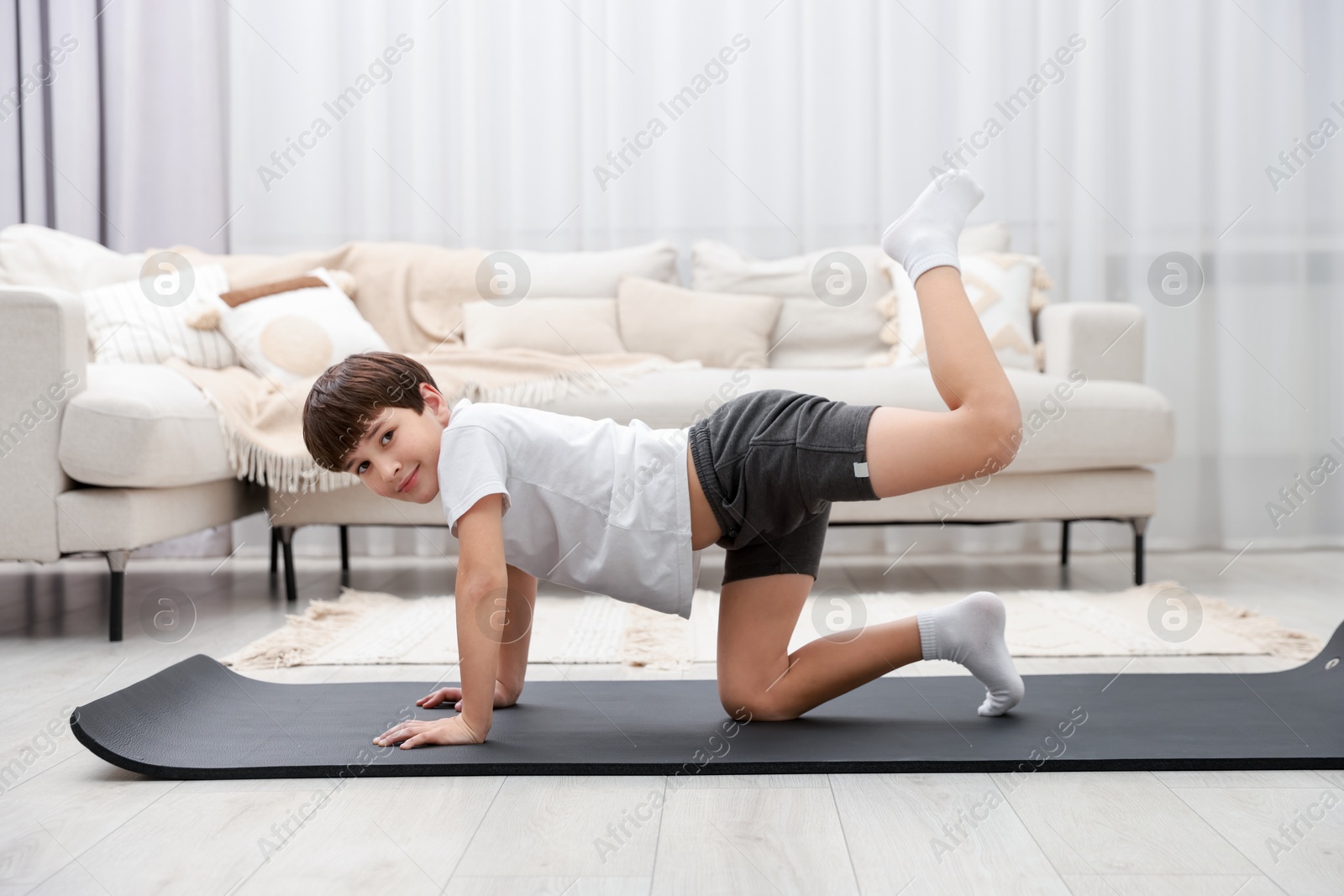 Photo of Boy doing exercise on fitness mat at home. Sport activity