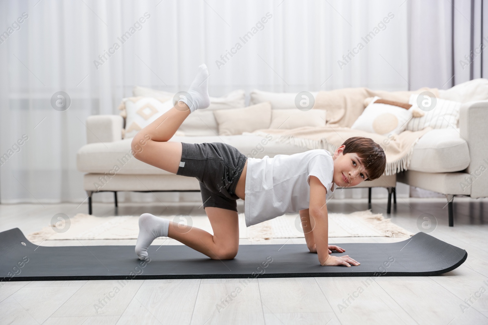 Photo of Boy doing exercise on fitness mat at home. Sport activity