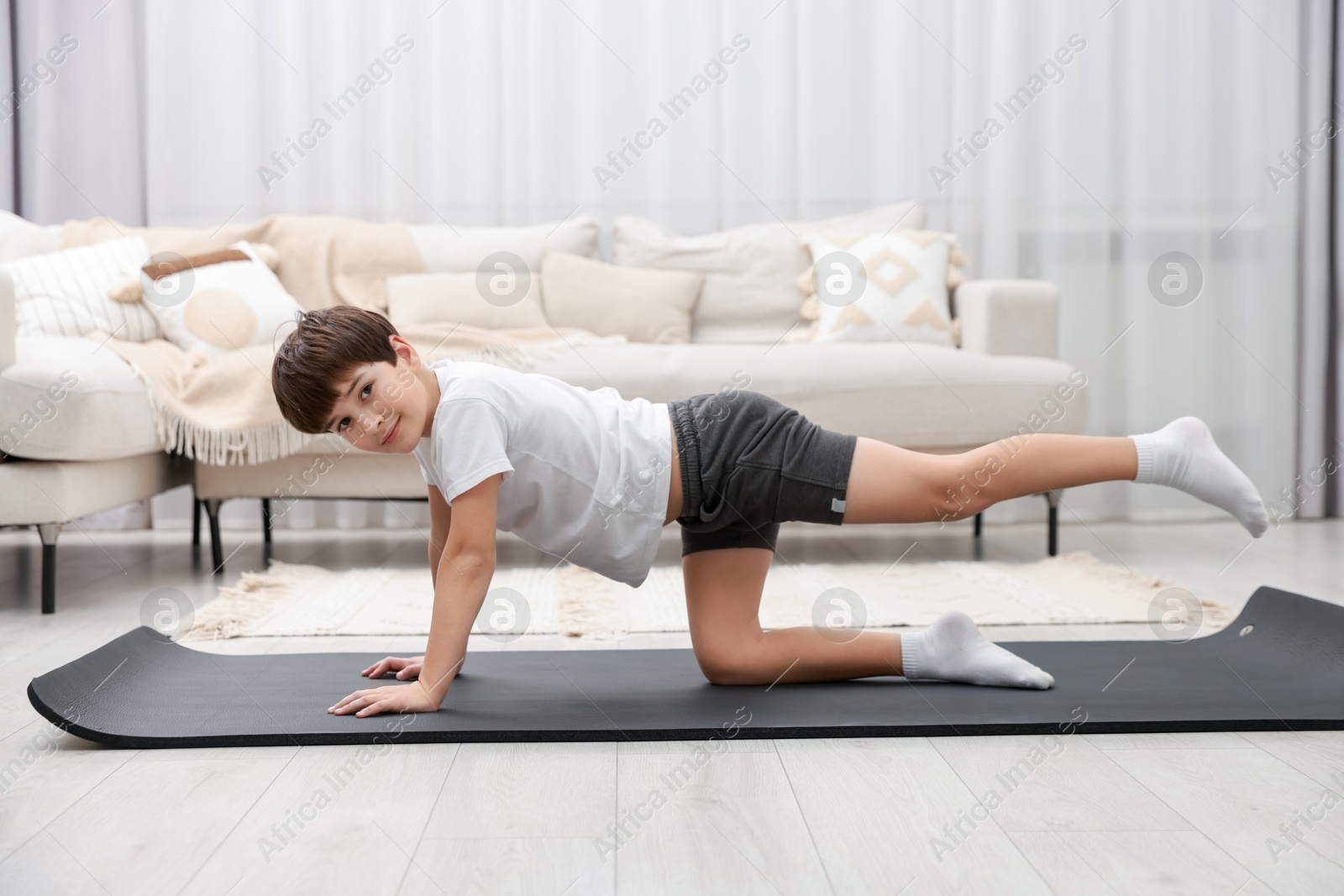 Photo of Boy doing exercise on fitness mat at home. Sport activity