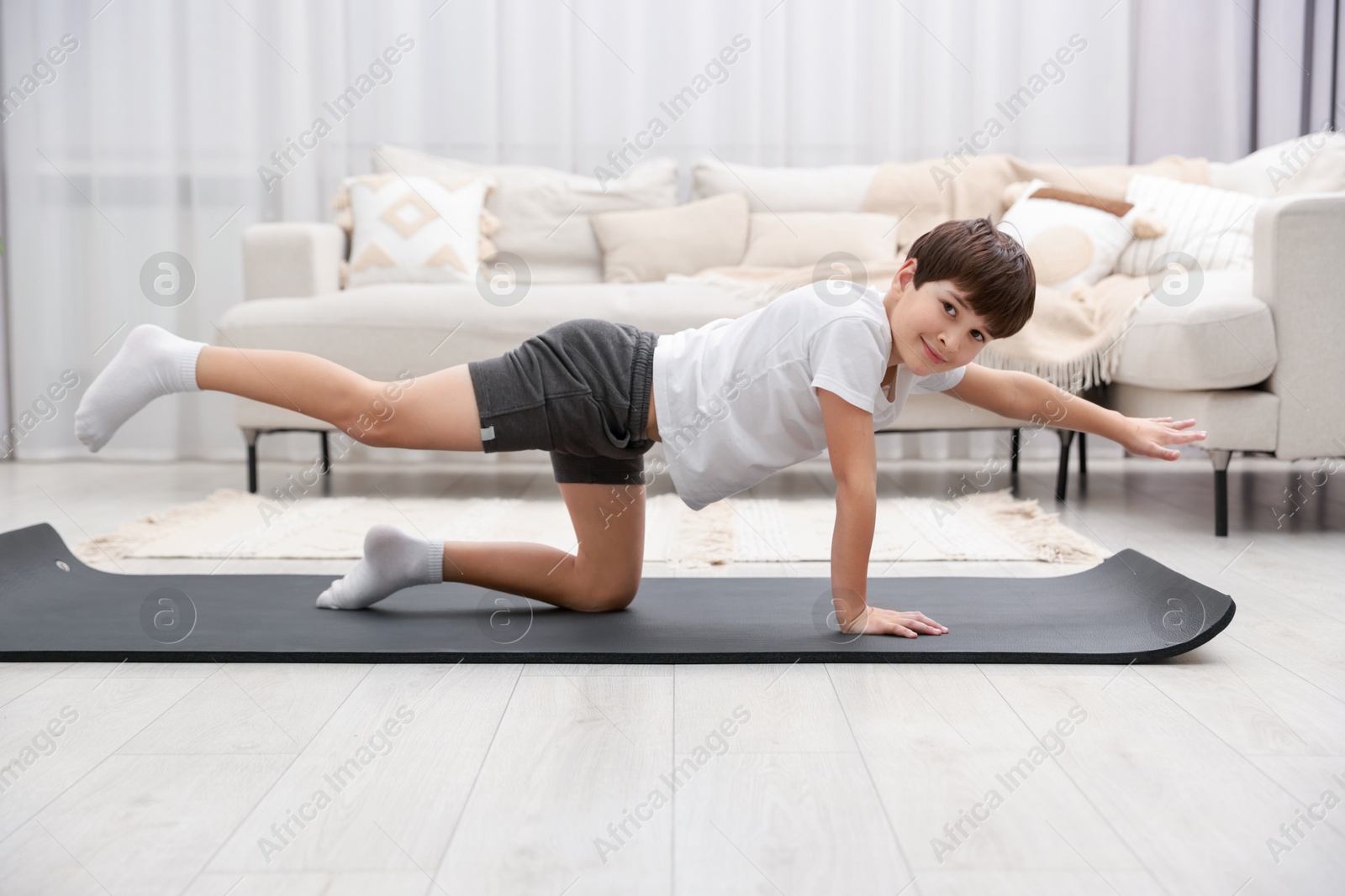 Photo of Boy doing exercise on fitness mat at home. Sport activity