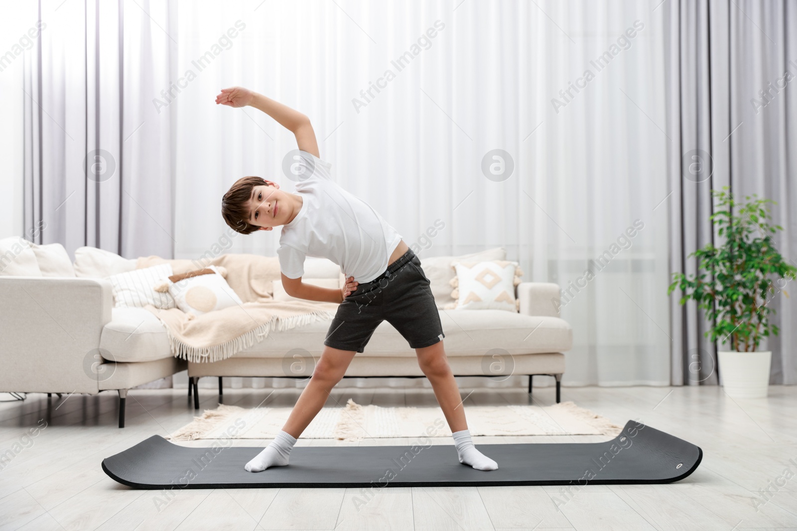 Photo of Boy doing exercise on fitness mat at home. Sport activity