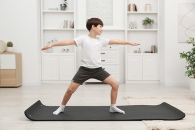 Photo of Boy doing exercise on fitness mat at home. Sport activity