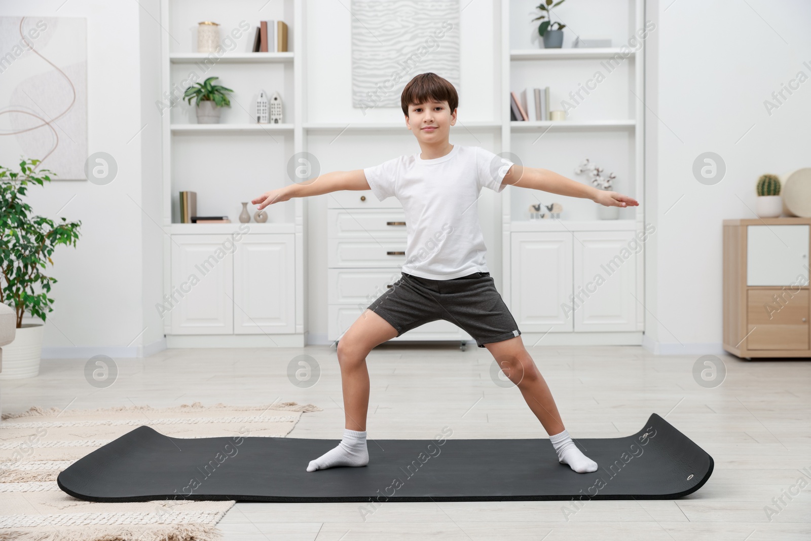 Photo of Boy doing exercise on fitness mat at home. Sport activity