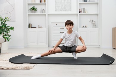 Photo of Boy doing exercise on fitness mat at home. Sport activity