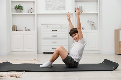 Photo of Boy doing exercise on fitness mat at home. Sport activity