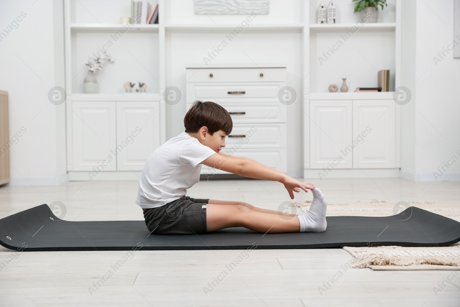 Photo of Boy doing exercise on fitness mat at home. Sport activity