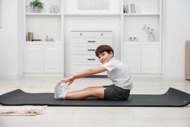 Photo of Boy doing exercise on fitness mat at home. Sport activity