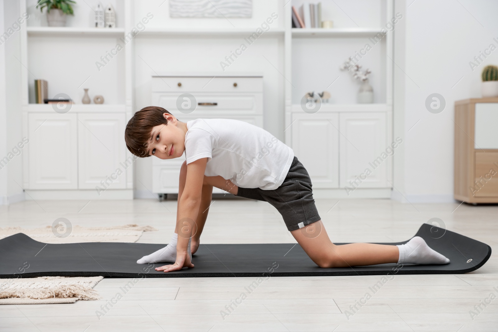 Photo of Boy doing exercise on fitness mat at home. Sport activity