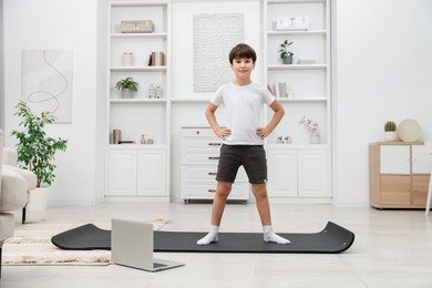 Photo of Boy having training with online coach via laptop at home