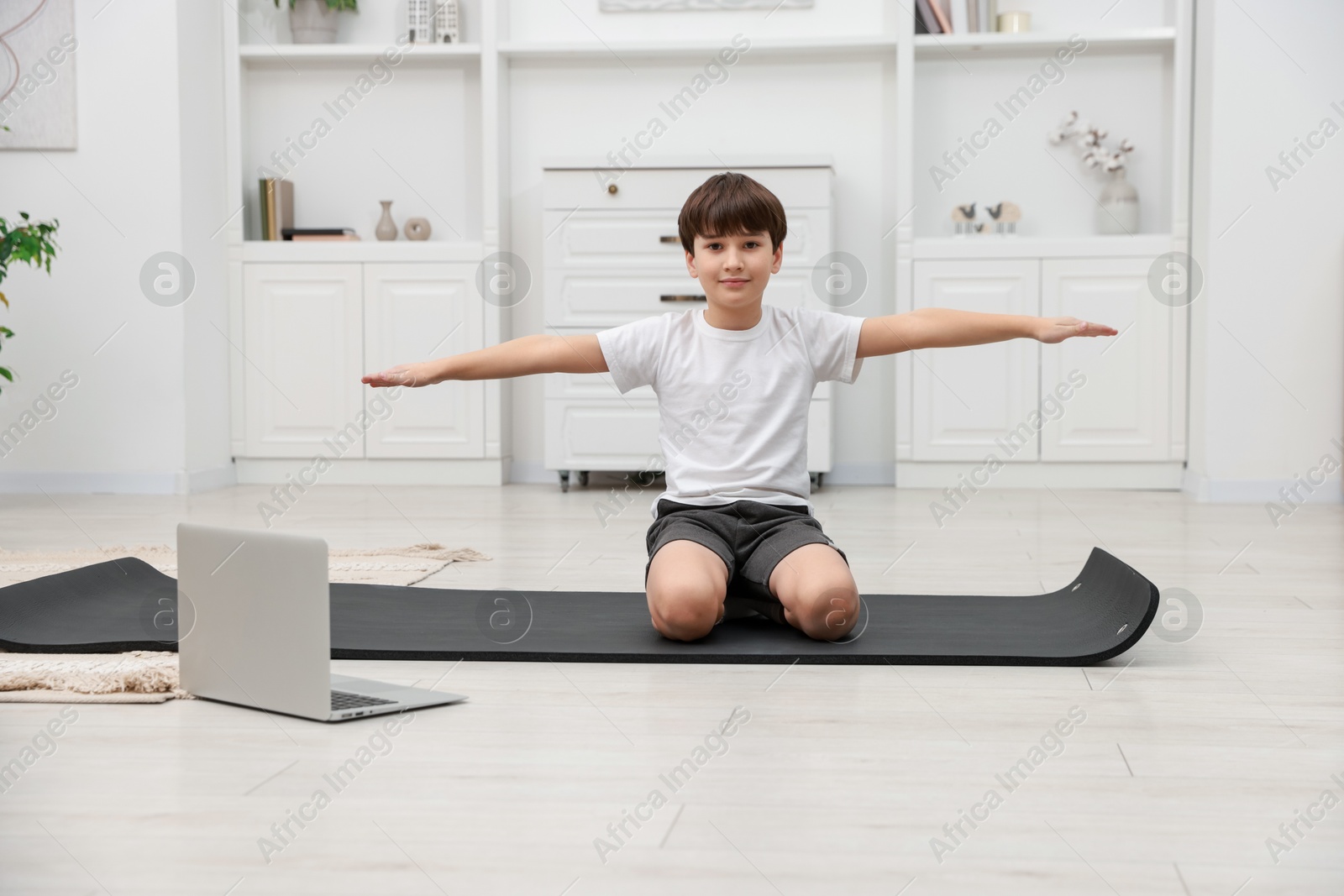 Photo of Boy having training with online coach via laptop at home