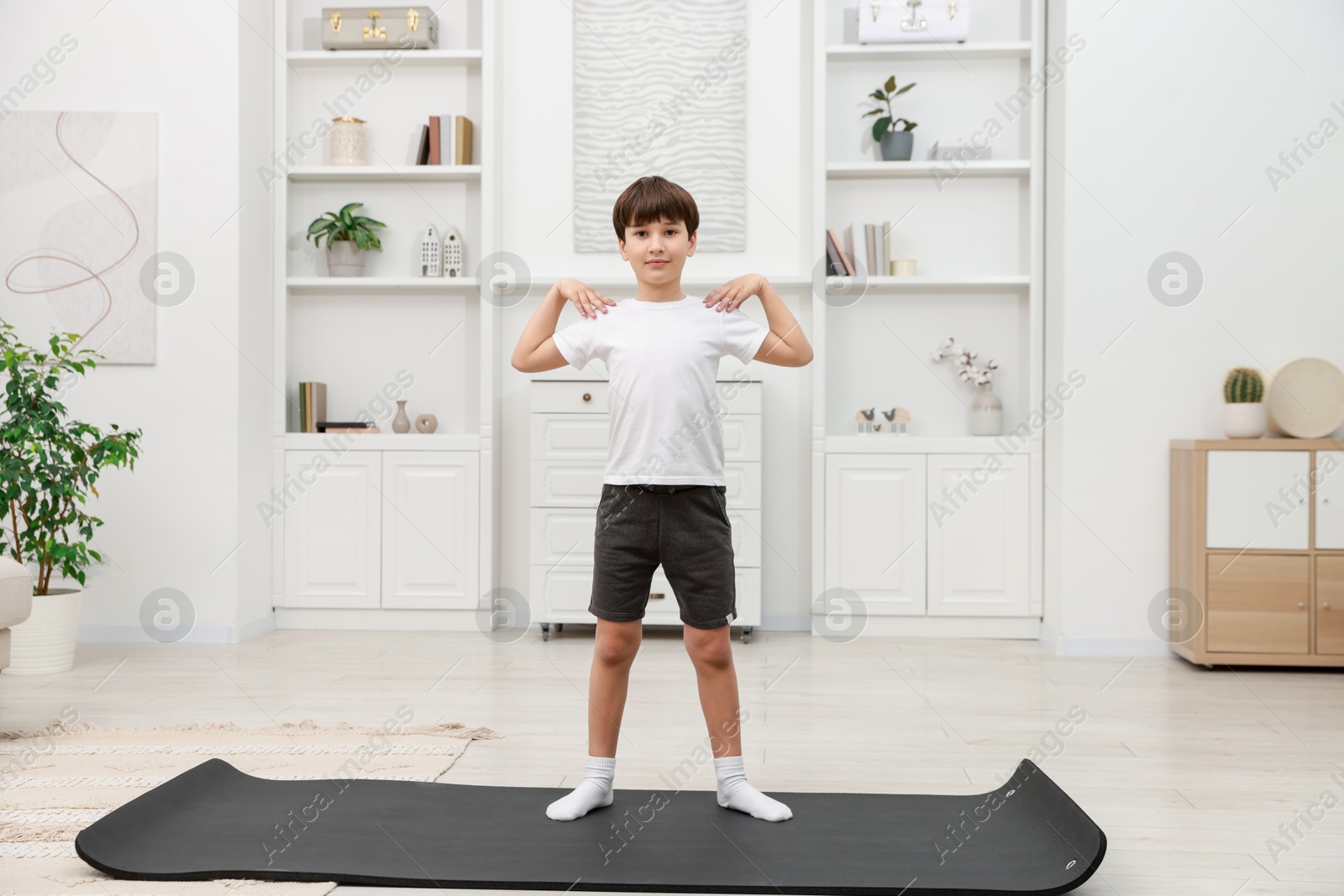 Photo of Boy doing exercise on fitness mat at home. Sport activity