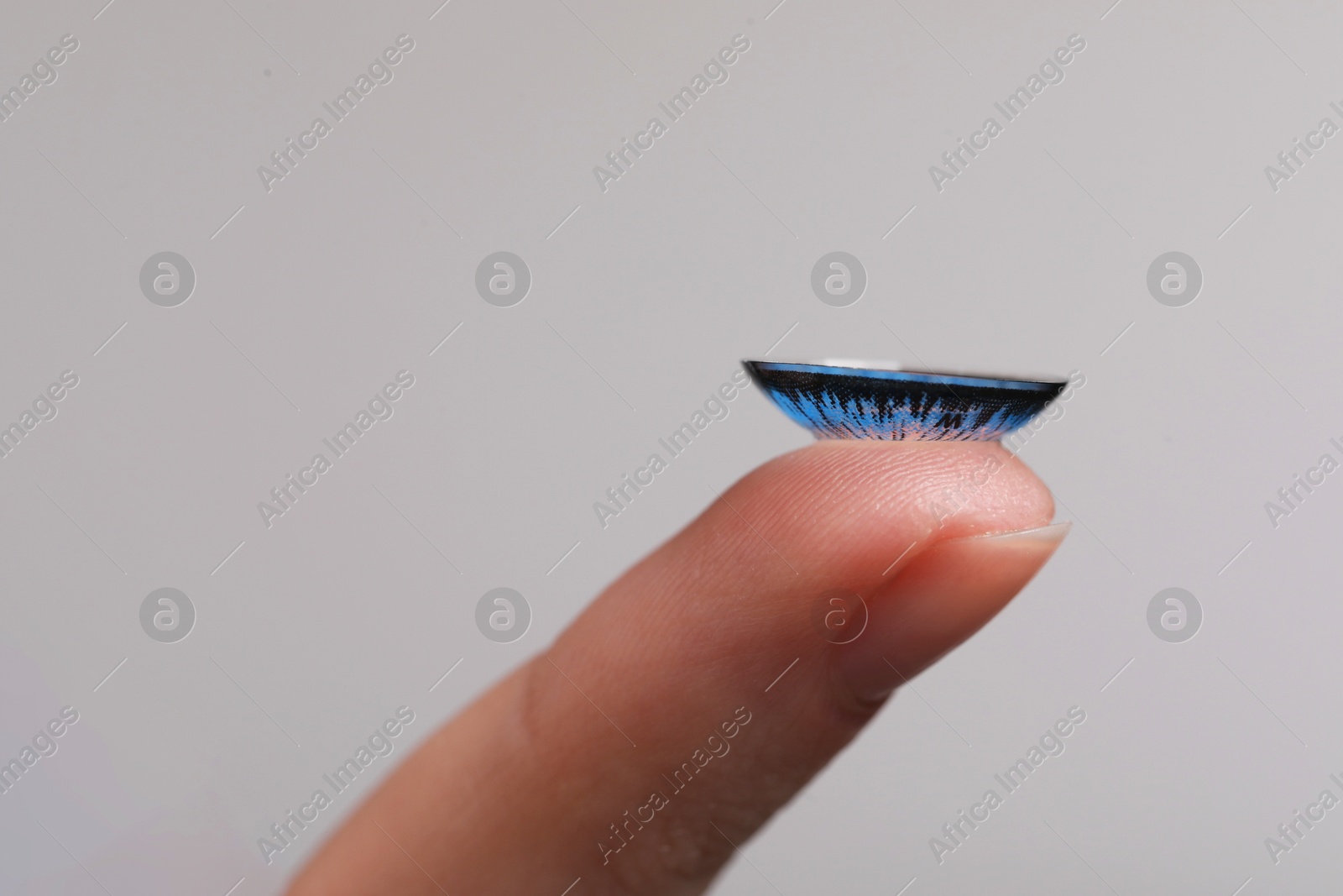 Photo of Woman with blue color contact lens on grey background, closeup