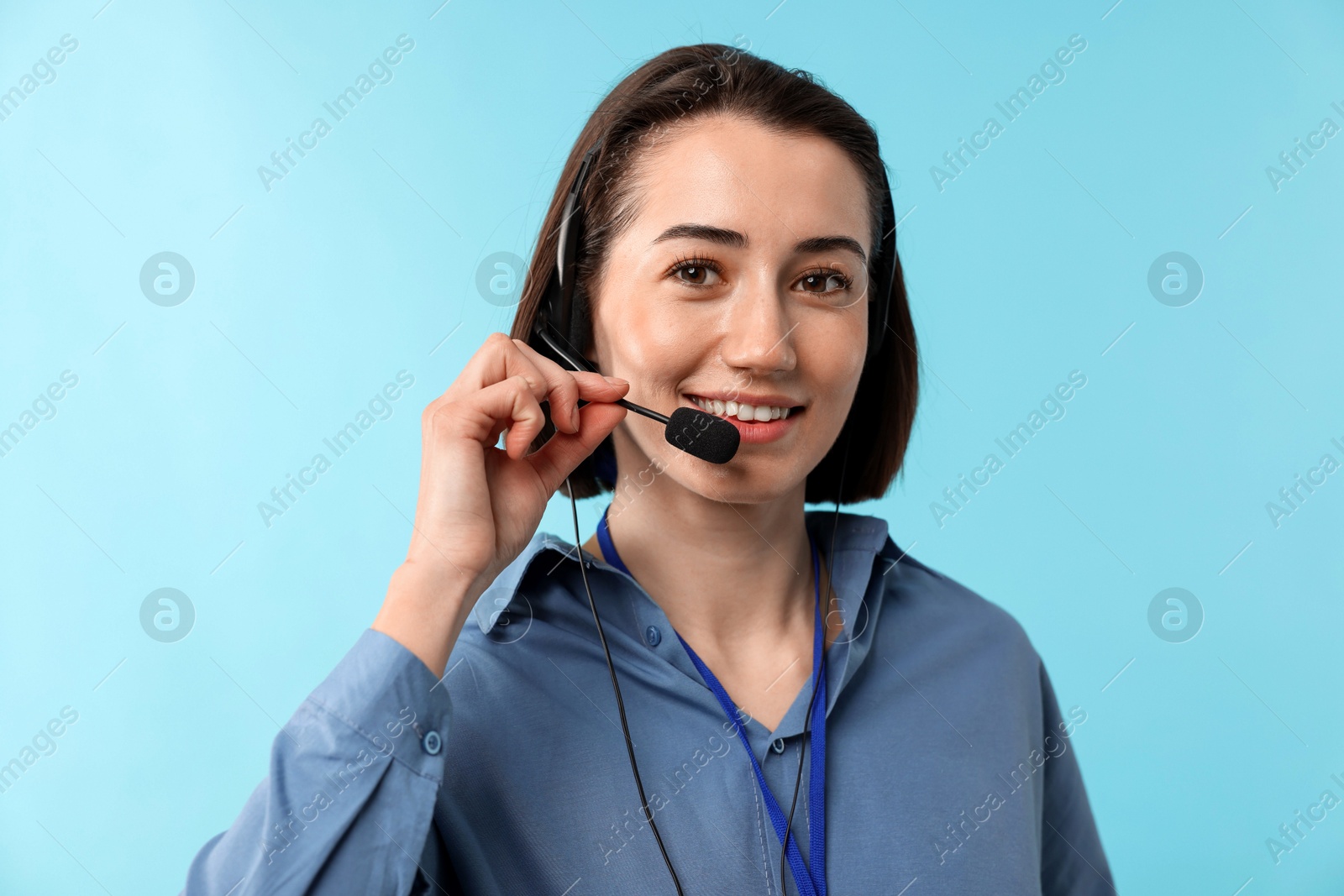 Photo of Technical support call center. Portrait of smiling operator on light blue background