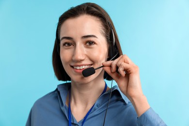 Photo of Technical support call center. Portrait of smiling operator on light blue background