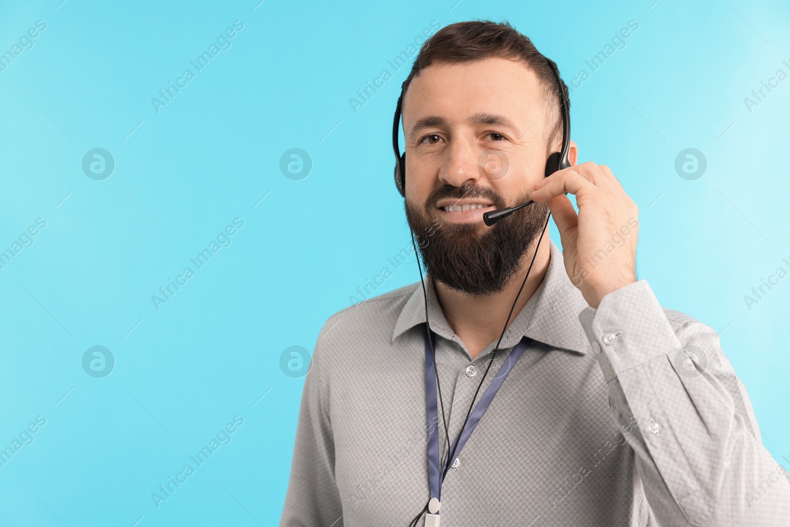 Photo of Technical support call center. Smiling operator on light blue background. Space for text