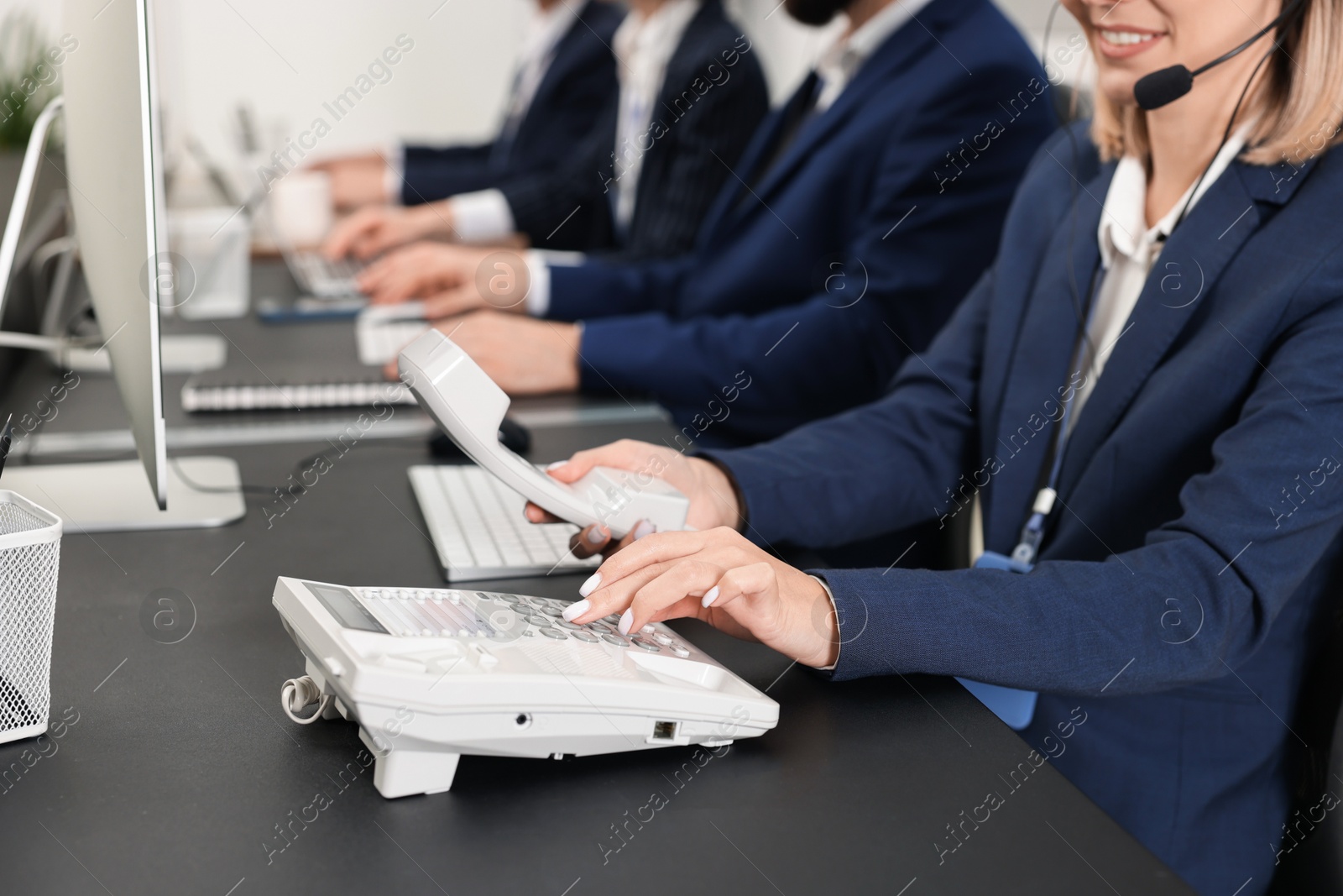 Photo of Technical support call center. Team of operators working at table in office, closeup