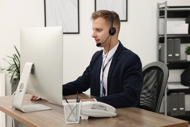 Photo of Technical support call center. Operator working at table in office