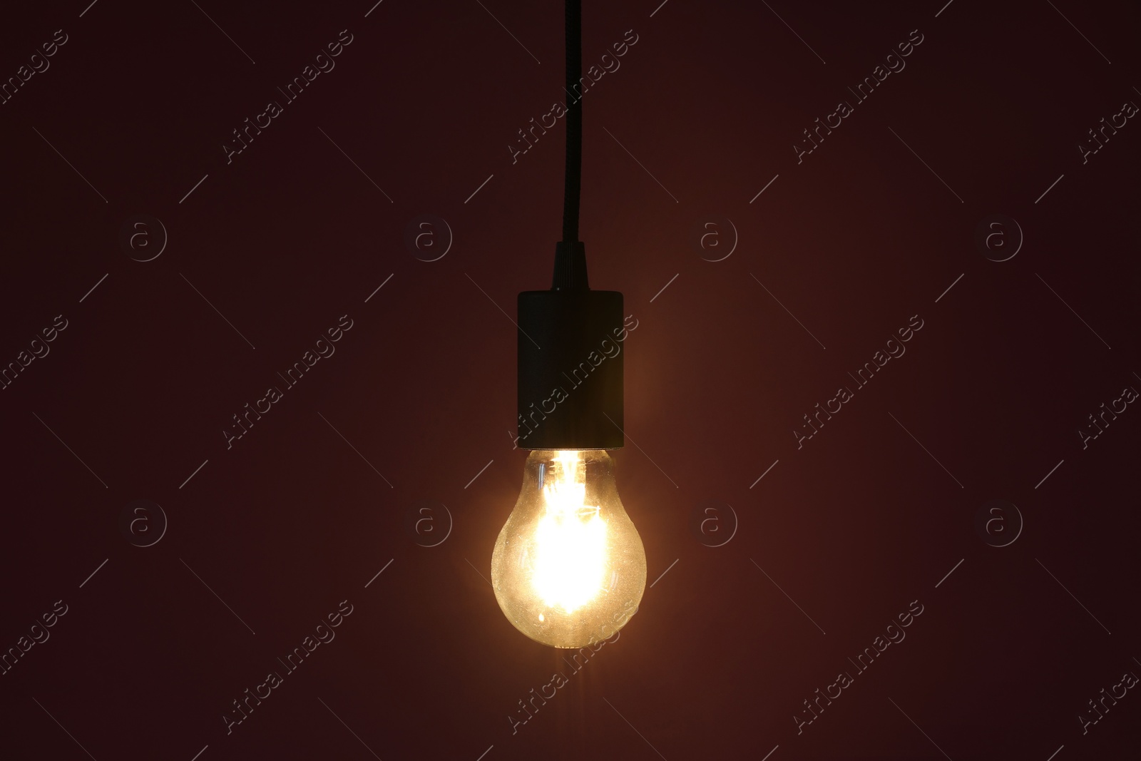 Photo of Glowing light bulb hanging on color background