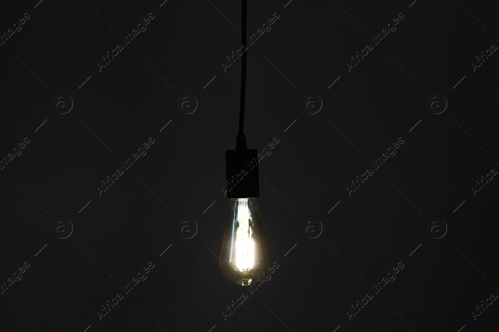 Photo of Glowing light bulb hanging on dark background