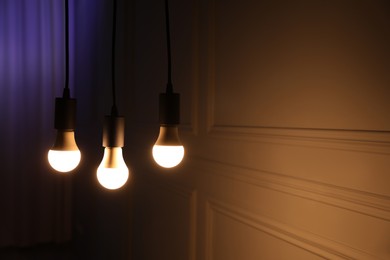 Photo of Glowing light bulbs hanging near wall, space for text