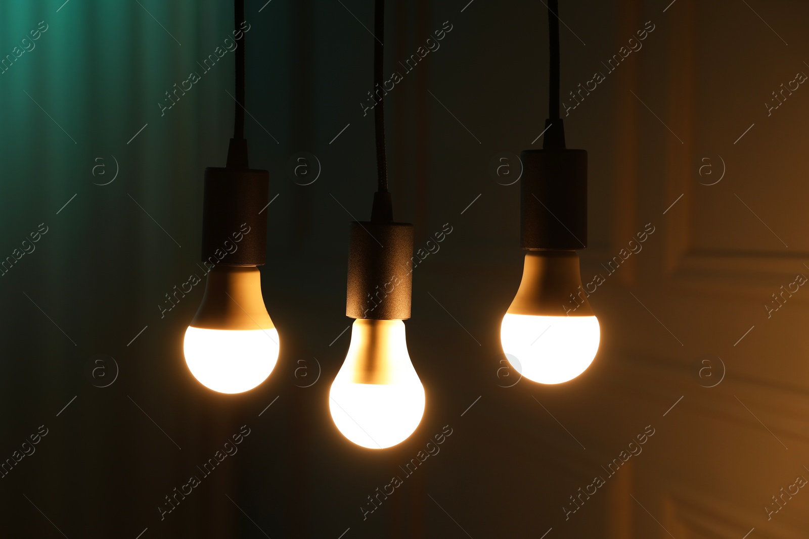 Photo of Glowing light bulbs hanging near wall, closeup