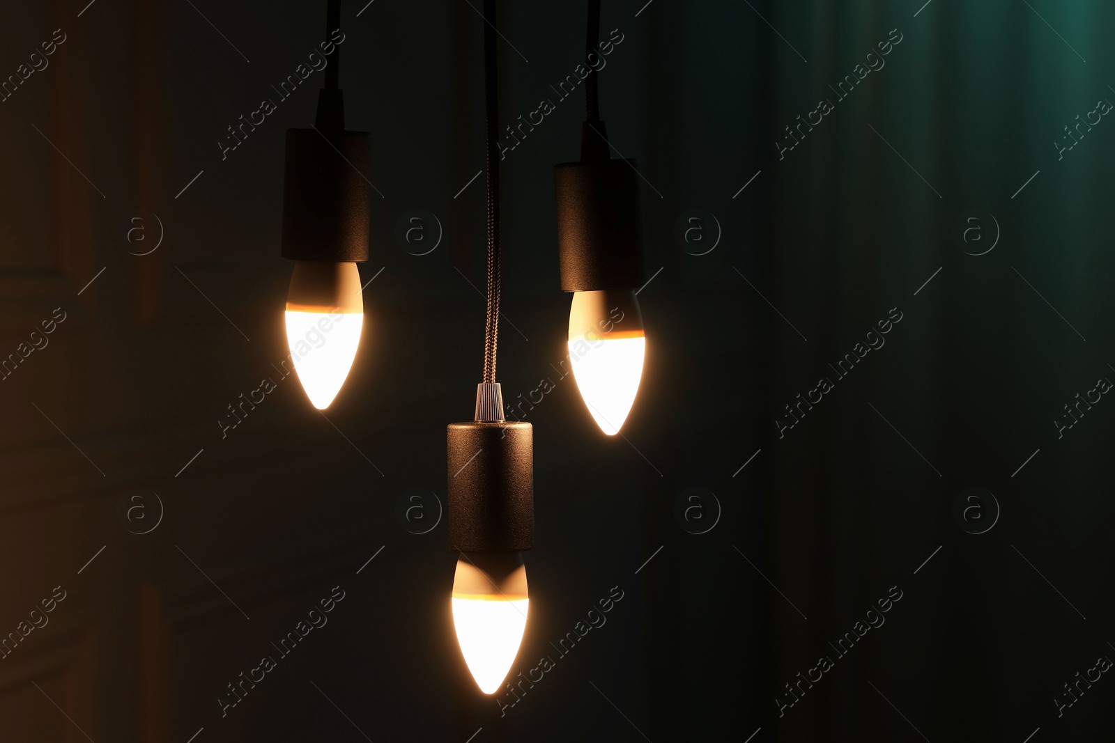 Photo of Glowing light bulbs hanging indoors, space for text