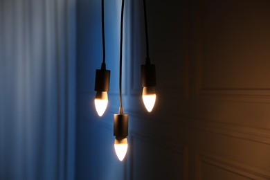 Photo of Glowing light bulbs hanging near wall indoors