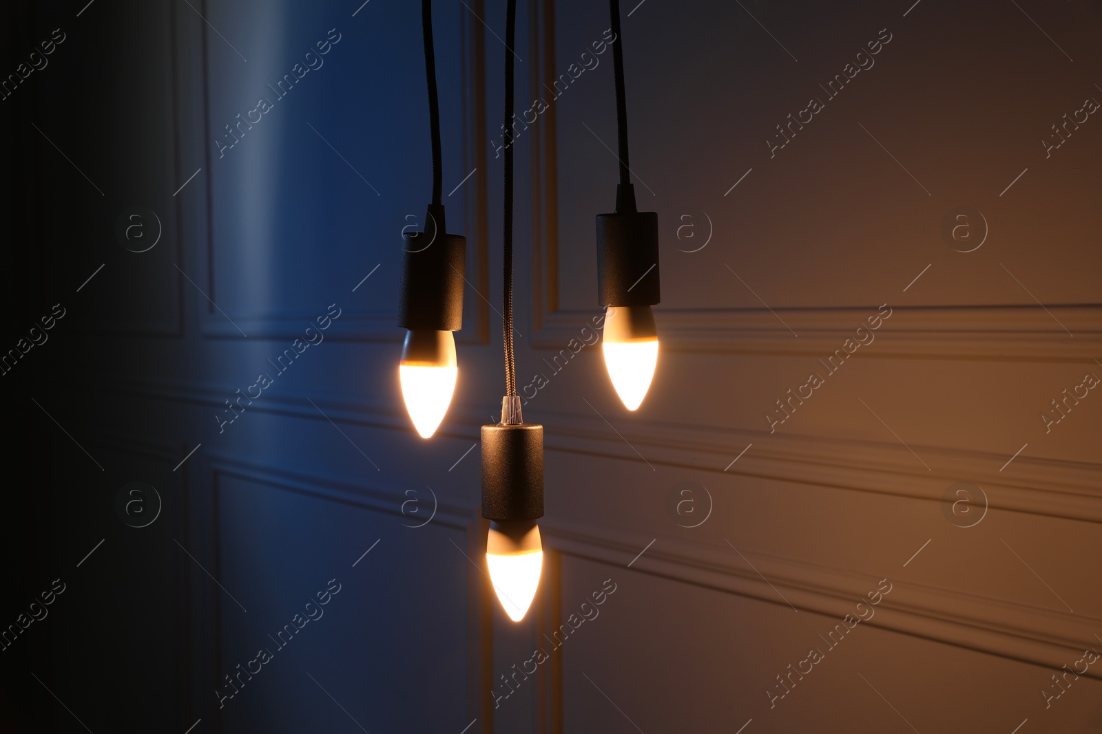 Photo of Glowing light bulbs hanging near wall indoors