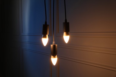 Photo of Glowing light bulbs hanging near wall indoors