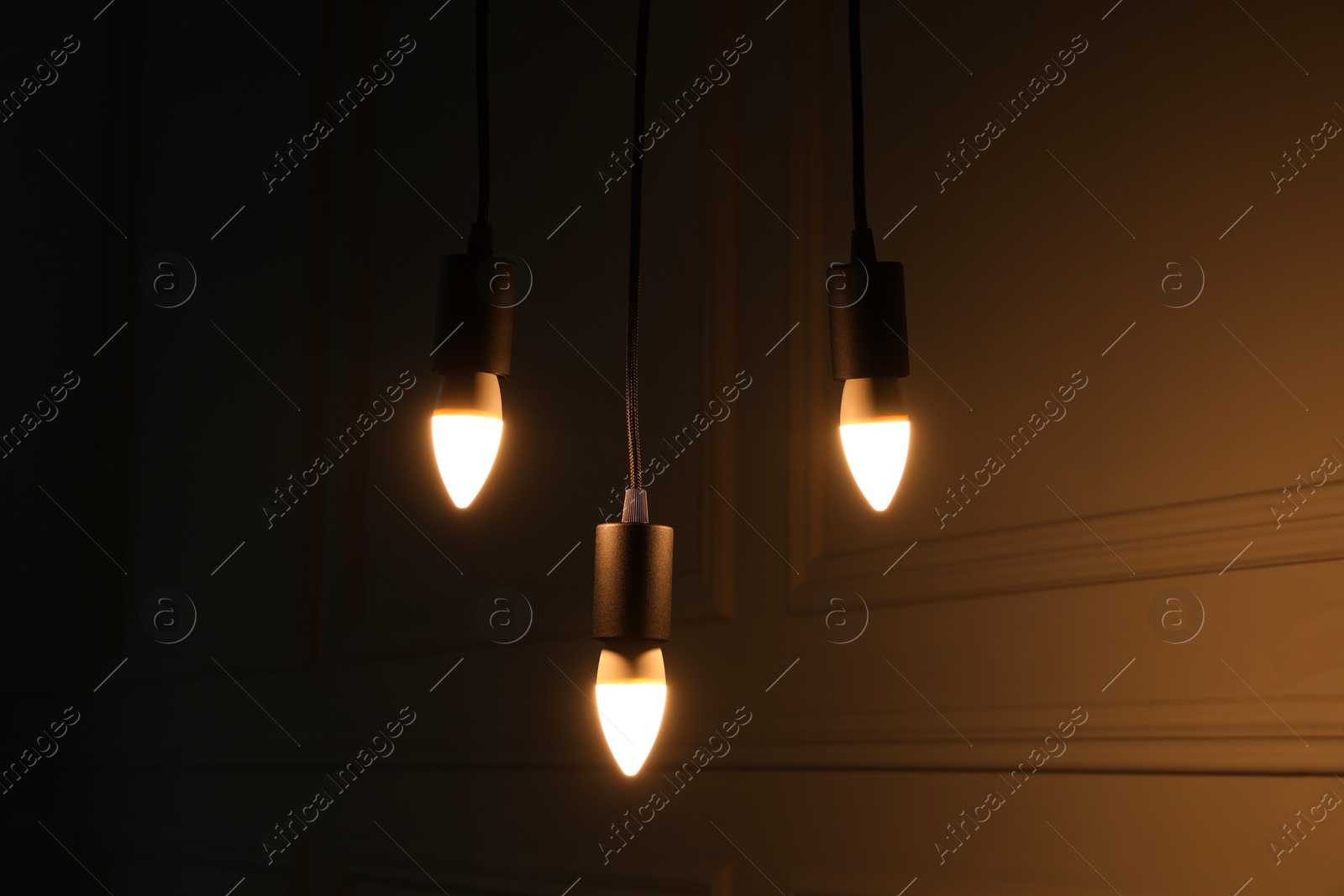 Photo of Glowing light bulbs hanging near wall indoors