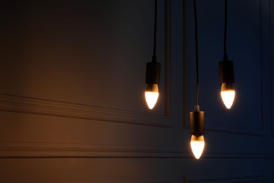 Photo of Glowing light bulbs hanging near wall, space for text