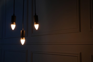 Photo of Glowing light bulbs hanging near wall, space for text